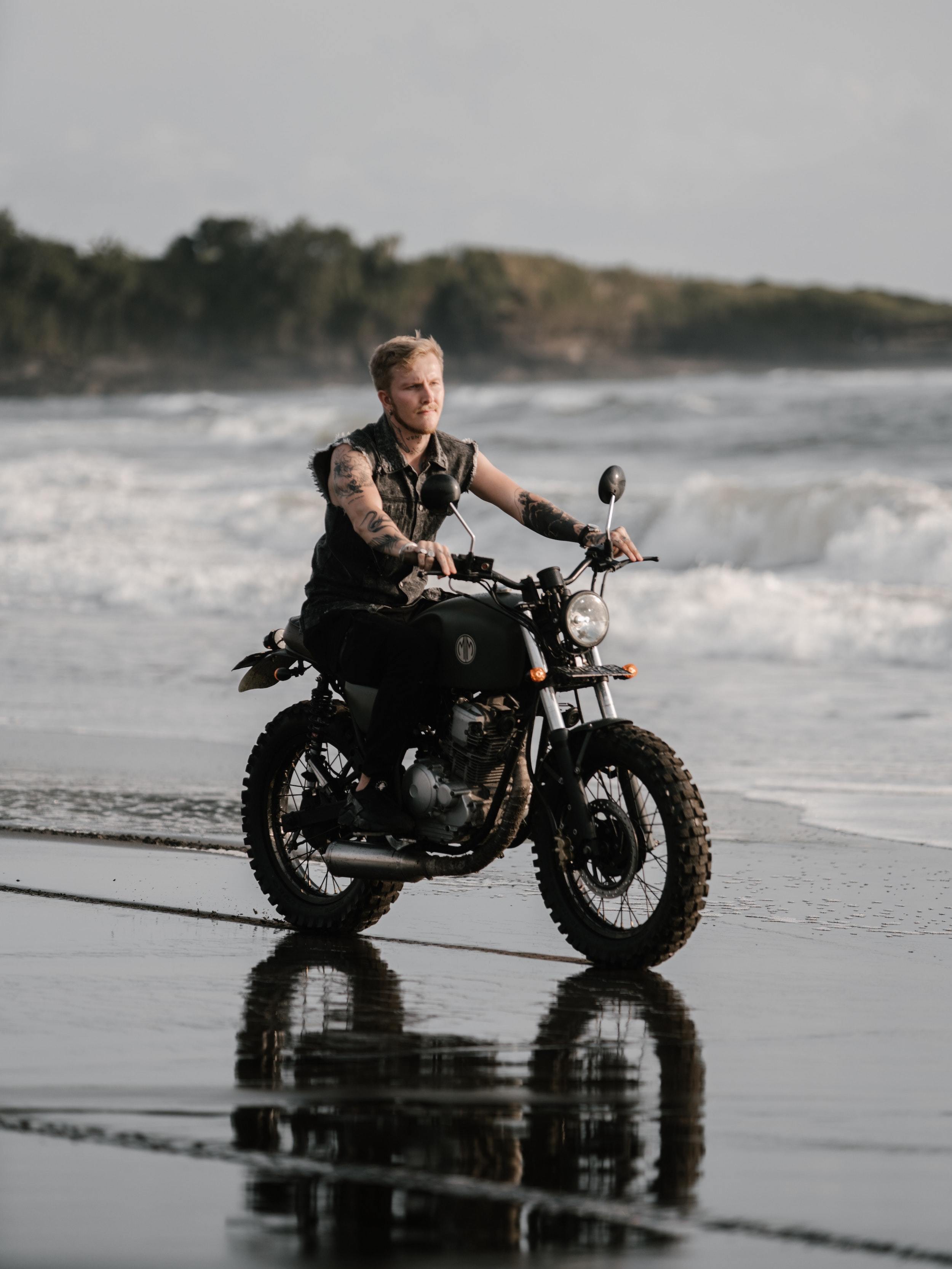 Tattooed motorcyclist riding bike along ocean coast in 4348221