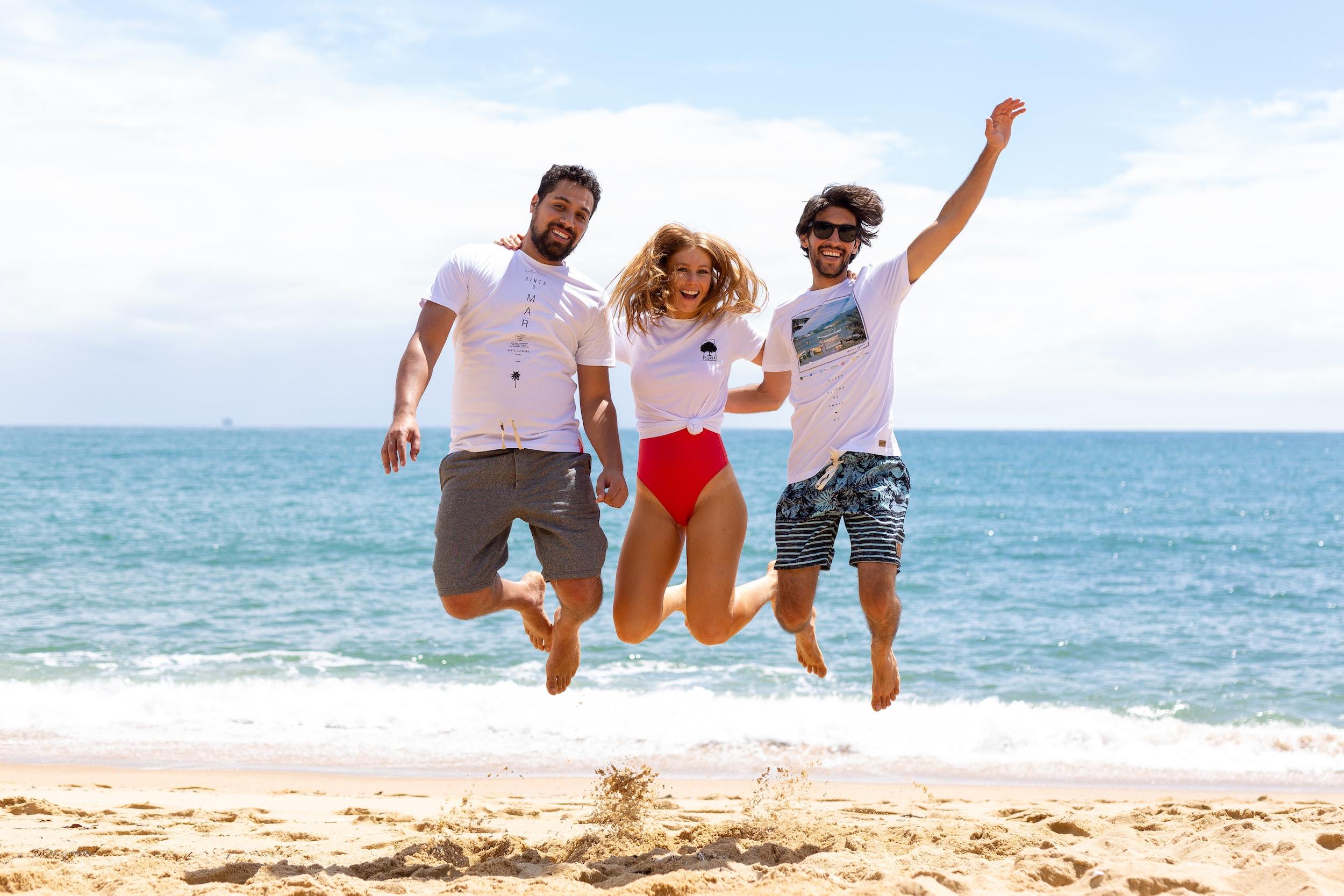 Two men and one woman jumping near shore 2231134